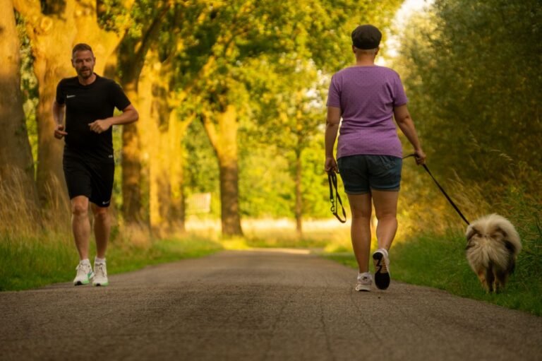 Man jogging and woman walking a dog on a picturesque outdoor path.